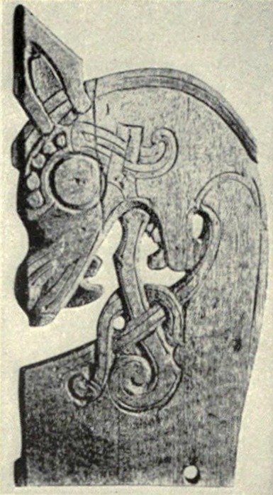 Eichenschnitzerei vom Gokstad-Fund, unvollständiger Bettpfosten C10408/1: Tierkopf mit Auge, Maul und durchbrochenem Flechtbandwerk am Plankenende (Encyclopædia Britannica 1911, Bd. 24, Tafel III Fig. 4, nach Gustafson — gemeinfrei, via Wikimedia Commons)