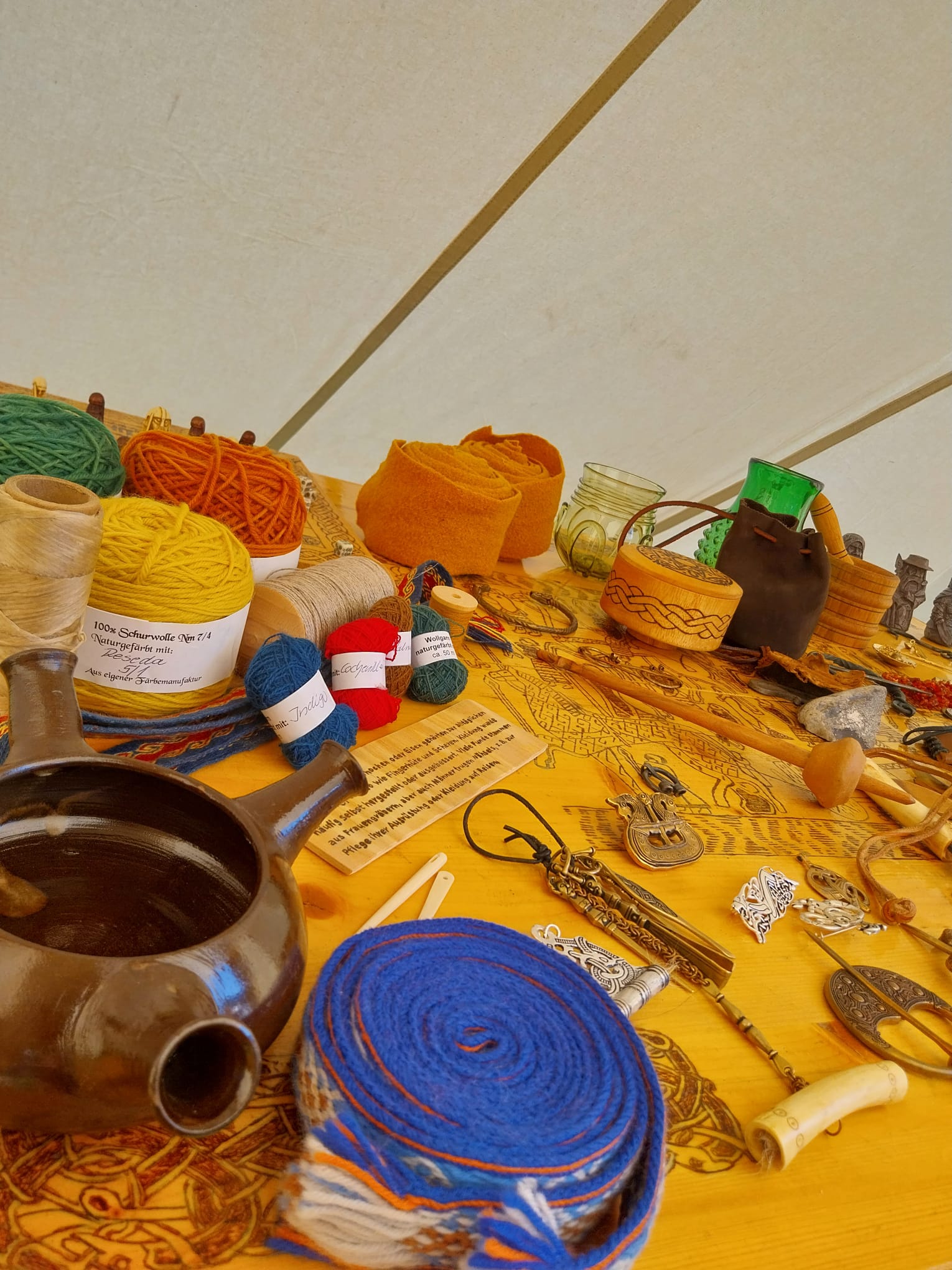 Im Museumszelt: die Textil-Ecke — naturgefärbtes Wollgarn aus eigener Färbemanufaktur, Brettchenborten, Spinnwirtel und Schmuck